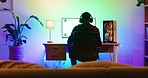 A back-shot of a young gamer playing and Winning. Online Video Game on His Powerful Personal Computer. The room and PC have multi-colored RGB Led Lights inside the CPU and a lamp on his desk.