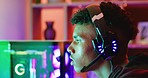 Guy playing video games on a computer with neon lights at night. Closeup of a focused esports gamer wearing a headset to chat to friends while streaming and competing in a multiplayer online session