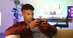 A young confident gamer playing on mobile looking at the camera and smiling. An African-American guy streaming video games from the phone. A cheerful guy sitting on a couch using his device.