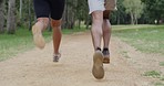 Closeup of fit couple legs running on a forest dirt road path. Active, athletic boyfriend and girlfriend bonding, training, exercising and jogging in social woods run. Man and woman in nature workout