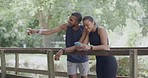 Two athletes using a phone to track their health and fitness progress while enjoying the view. Smiling man and woman feeling happy after a completed exercise workout while training in a nature park