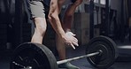 Male weight lifter applying chalk to hands before training in a gym. A determined muscular man using a barbell during his heavy weight lifting exercise. A sporty powerlifter preparing to bench press