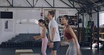 Fit group of people exercising and jumping on wooden boxes during a HIIT fitness gym class with a trainer. Diverse team of active, athletic, sporty man and women performing cardio training or workout