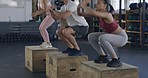Group of fit people exercising and jumping on wooden boxes during a HIIT fitness class with a trainer. Diverse team of active, athletic, sweaty man and women performing cardio training and workout