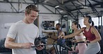 Coach using a digital tablet in a gym while training a group fitness class. Portrait of a muscular young male trainer smiling while browsing health and wellness data online during an aerobics workout
