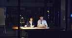 A business man and woman working together overtime to complete a project before the deadline. Young corporate people in the office late at night or evening completing paperwork on a nightshift