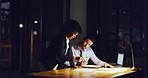 Two businesspeople having a discussion while working late in an office. Female leader or mentor giving instructions or ideas on paperwork with colleague at night. Accountants trying to reach deadline