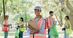 Female volunteer with clipboard in park. Group of people doing volunteer or charity work by cleaning up litter in a park in their community. Diverse people conducting neighbourhood cleanup program