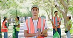 Portrait of a young volunteer leader supervising a park cleaning project. A group of NGO employees wearing uniform working in a public garden. A team picking up litter together in a field 