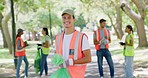 Portrait of a young man cleaning the park with eco friendly community. Responsible council workers, activists or volunteers in orange and yellow vest picking up garbage for a clean, green environment