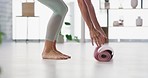 A woman rolls out a yoga mat on the floor in a yoga fitness training room. Active and fit barefoot prepares for a home workout, to live a healthy lifestyle with a balanced mind and body in the lounge