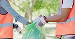 Closeup of people cleaning the park for eco friendly environment. Responsible council workers, activists or volunteers in orange vest throwing recycle or reusable material in a plastic bag