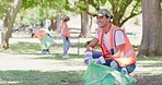 Happy young man cleaning a park in an eco friendly community. Responsible council workers, activists or volunteers collecting garbage and litter for a sustainable, clean and safe environment
