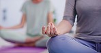 Closeup of a woman meditating with mudra hand gesture during a fitness class in a yoga studio. Calm, relaxed and focused lady sitting with legs crossed while praying quietly for peace and zen energy
