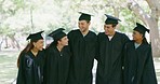 Portrait of a group of university or college graduates in mortarboards and gowns standing outside together at their graduation ceremony. Proud students taking photos after their educational success