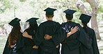 Rear of students standing together at graduation. Group of successful graduates or classmates in cap and gowns feeling accomplished after having achieved their diploma certificates at university