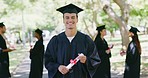 Portrait of a university student at a graduation ceremony outdoors. Young man holding a diploma while celebrating his accomplishment and achievement. Getting a good education for a successful future