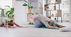 Mature yoga women holding childs pose in a zen studio class. Diverse group of yogis stretching their back and shoulders on mats. Finding inner mental balance and peace with a gentle holistic exercise