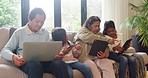 Happy family bonding with kids while using a laptop, digital tablet and phone with the home wifi. Children playing on multimedia devices, watching videos together in grandparents home on the weekend