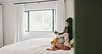 Mother and children playing games on a tablet sitting on a bed in a bedroom. Cute mom entertaining her kids with a digital touchscreen device in their home. Single parent typing with her daughters