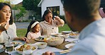 Multi generation family sharing a meal at a table in their backyard. Asian kids, grandparents and parents eating lunch and bonding at an outdoor dining area at home. Celebrations and holidays