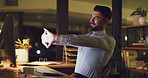 Dedicated business man stretching at his desk while working on a computer late at night in the office. Tired and overworked corporate professional suffering from burnout and trying to meet deadlines