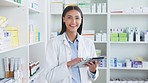 Portrait of a cheerful and friendly pharmacist using a digital tablet to check inventory or online orders in a chemist. Young latino woman using pharma app to do research on medication in a pharmacy