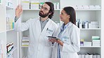 Pharmacists working together stocktaking medication at the pharmacy. Two healthcare professionals discussing a patient prescription at a dispensary. Two medical doctors talking about medicine tablets