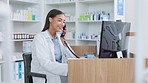 Pharmacist woman answering the telephone and giving advice to customer on flu shot treatment options in pharmacy. Chemist assisting remote client by checking medicine stock on their computer database