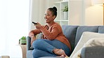 A comfortable woman at home watching her favorite comedy TV show while having some coffee. A young female enjoying some entertainment in her house on a weekend. Lady laughing and smiling at a movie