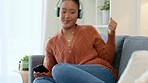 Cheerful african woman using phone and wearing headphones and listening to music while relaxing at home. Happy young woman lying on cozy couch and enjoying her favourite song during leisure time