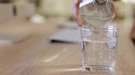 Hands pouring fresh bottled water into a glass for a refreshment and to prevent dehydration. A business woman feeling thirsty and pouring herself an alkaline drink to get her daily intake of liquid 