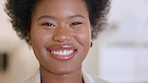 Portrait of the face of a cheerful businesswoman smiling and laughing while standing alone in an office at work. Headshot of one confident and happy black female advocate working at a legal company
