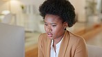 Woman looking stressed while trying to reach a deadline and working on a desktop computer at work. One black female corporate professional looking unhappy and overwhelmed while reading an email