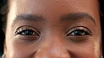 Cosmetic details of a smiling and positive black woman with pretty hazel eyes blinking and staring into the camera. Closeup of female eyes with beautiful lashes looking confident and carefree