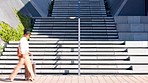 A woman carrying a suitcase and leaving on a business trip while walking in the city alone. Corporate professional traveling for work with luggage in town. Female entrepreneur commuting to work