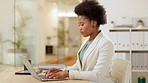 African businesswoman using laptop to complete tasks, type an email or to do research for her project. Happy afro female entrepreneur using technology and planning for success in her startup agency