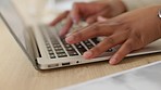 Closeup of a business woman browsing on a laptop keyboard in an office. Hands of one productive entrepreneur typing emails and compiling online reports while doing research and planning in a startup