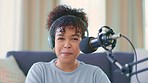 Portrait of a cheerful woman recording a podcast while wearing headphones and talking over a microphone for her talk show. Funny African blogger using audio equipment and doing a live radio broadcast