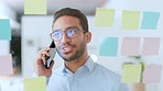 Young business man talking on his phone while brainstorming and planning strategy on a glass wipe board at work. Male corporate professional discussing ideas during a call in the office boardroom