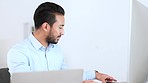 Young business man on a phone call with a colleague about marketing strategies while doing research on a desktop computer online. Happy corporate professional networking and reading emails on a pc