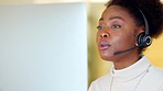 Black call center agent wearing a headset and working in a modern office. Young African American woman talking on a video conference. Female focused while explaining and working in customer care 