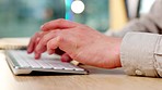 Closeup of hands and fingers typing fast on a computer keyboard on his office desk. Male student or businessman writing an email, doing research, working on his essay or messaging someone online