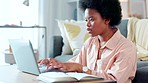 Focused female student typing an academic essay or working on homework assignment while sitting alone at home. Young african university or college student with afro writing an email looking busy