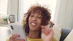 Cheerful african woman using phone and wearing headphones and listening to music while relaxing at home. Happy young woman lying on cozy couch and enjoying her favourite song or meditation podcast