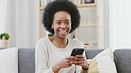 Portrait of a black woman smiling and laughing while texting on a phone at home. Happy female chatting to friends on social media, browsing online and watching funny internet memes while relaxing