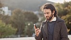 Portrait of cheerful smiling male answering his phone outside. Young entrepreneur talking in excitement as he receives good news about a business deal. Calling a friend  on a winter walk