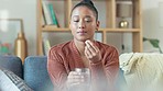 Depressed woman taking medication for mental health and wellness sitting inside her home. Sick young female drinking antibiotics for flu virus or a cold infection. Daily supplements for immune system