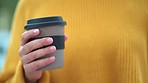 Close up of a latino person holding a cup of coffee. Casual tourist with manicured hands and nails getting coffee while exploring. Individual relaxing with beverage with blurred traffic in background