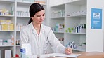 A female pharmacist or clerk working behind the pharmacy counter of a clinic or hospital, selling or prescribing medicine or writing dosage instructions. A caucasian doctor ready to advise patients.
